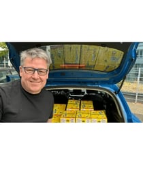 Martin smiling in front of his car boot packed full of Honey Mango boxes, ready to deliver to Indian clients across Germany in 2023